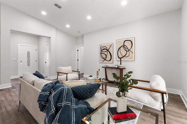 living area with recessed lighting, visible vents, baseboards, and wood finished floors