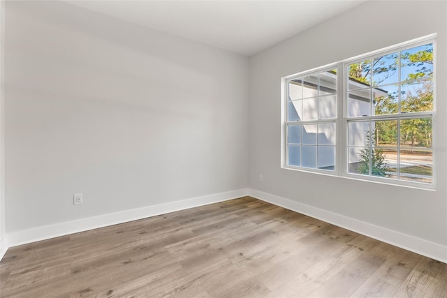 spare room with baseboards and wood finished floors