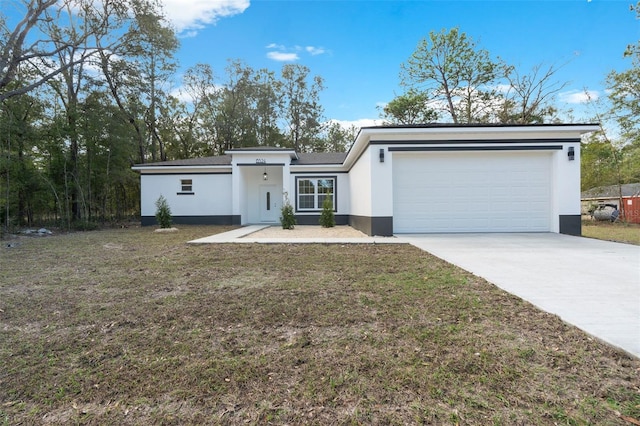 view of front facade with stucco siding, concrete driveway, a front lawn, and a garage