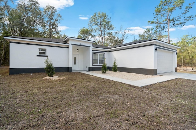 view of front facade with stucco siding, an attached garage, and driveway