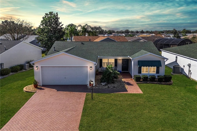 ranch-style home featuring cooling unit, a garage, and a lawn