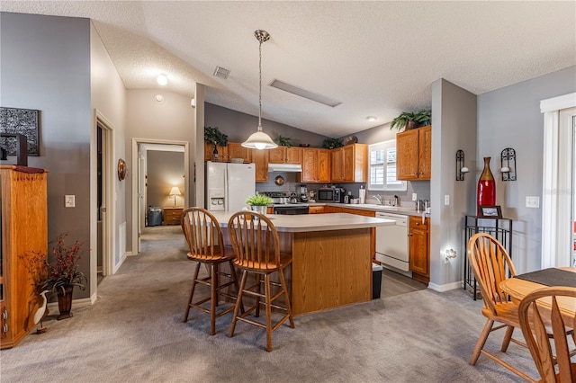 kitchen featuring vaulted ceiling, a kitchen island, pendant lighting, carpet, and white appliances