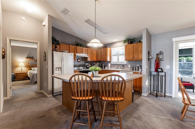 kitchen with pendant lighting, lofted ceiling, a center island, dark colored carpet, and white refrigerator with ice dispenser