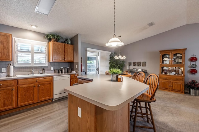 kitchen with sink, a breakfast bar area, a center island, and dishwasher