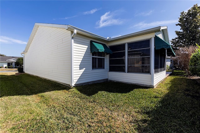 view of side of home with a lawn and a sunroom