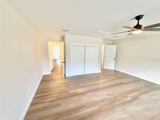 unfurnished bedroom with ceiling fan, a closet, light hardwood / wood-style flooring, and a textured ceiling