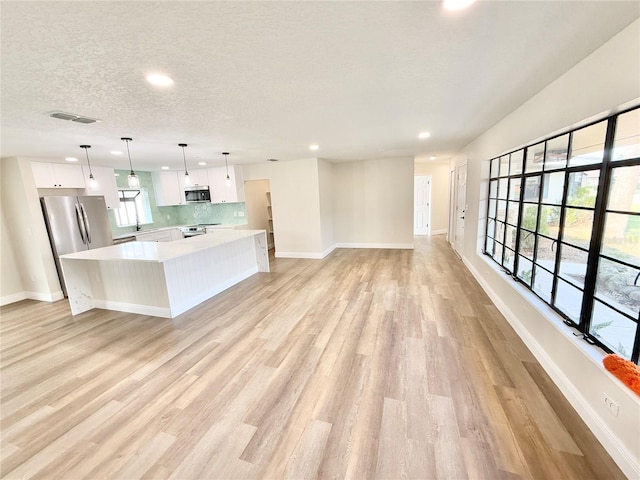 kitchen featuring a large island, hanging light fixtures, white cabinets, and appliances with stainless steel finishes