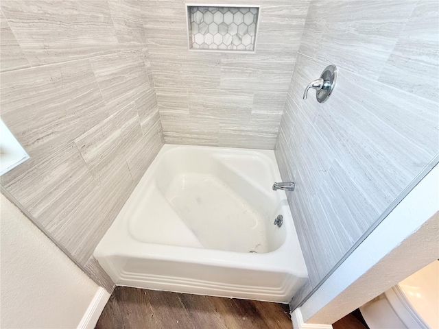 bathroom with hardwood / wood-style flooring and a tub to relax in