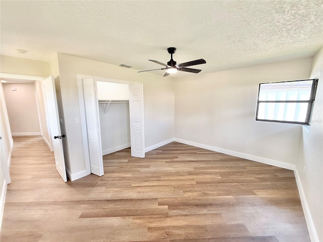 unfurnished bedroom featuring ceiling fan, light hardwood / wood-style flooring, a closet, and a textured ceiling