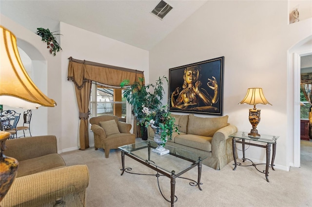 carpeted living room with high vaulted ceiling