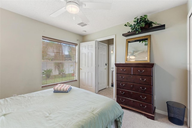 carpeted bedroom featuring ceiling fan and a textured ceiling