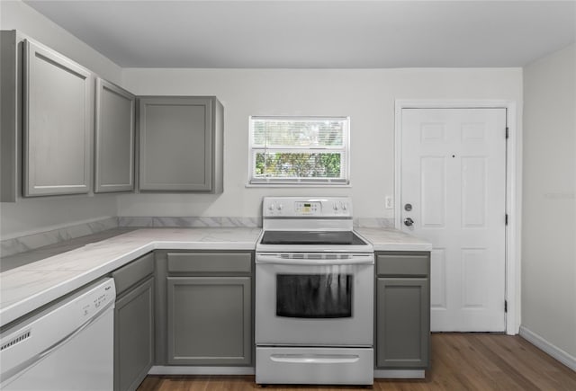 kitchen featuring dark wood-type flooring, white appliances, and gray cabinetry