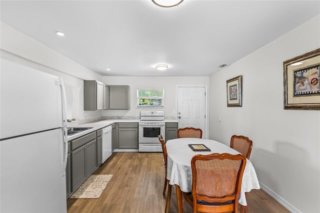 kitchen with white appliances, gray cabinets, and light hardwood / wood-style flooring