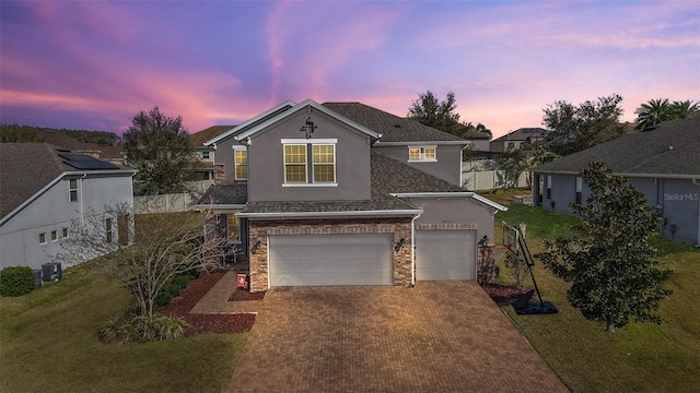 view of front property with a garage, a yard, and central air condition unit