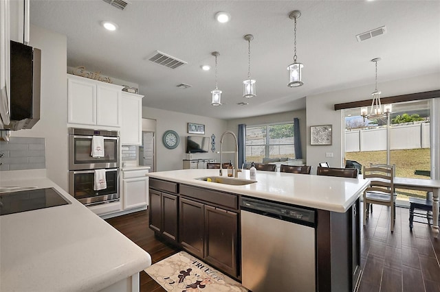 kitchen featuring pendant lighting, an island with sink, sink, white cabinets, and stainless steel appliances