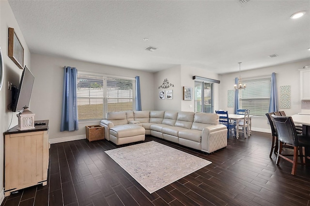 living room featuring dark wood-type flooring, a textured ceiling, and a chandelier