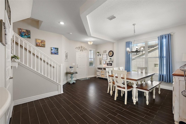 dining space featuring dark hardwood / wood-style flooring, a textured ceiling, and a notable chandelier