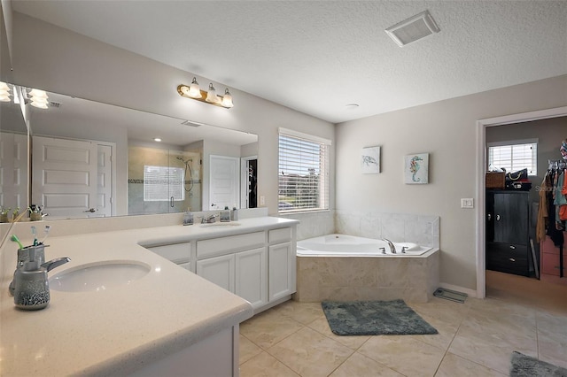 bathroom with tile patterned flooring, plus walk in shower, vanity, and a textured ceiling