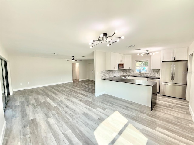 kitchen featuring sink, white cabinets, decorative backsplash, kitchen peninsula, and stainless steel appliances