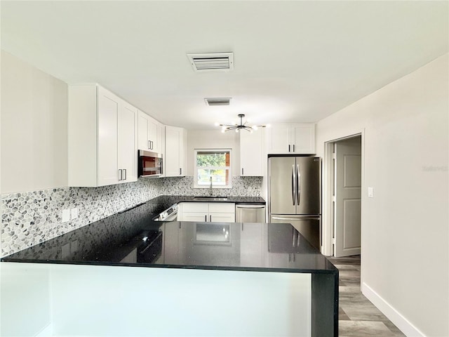 kitchen with sink, stainless steel appliances, kitchen peninsula, and white cabinets