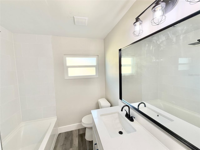 full bathroom with vanity, tiled shower / bath, hardwood / wood-style flooring, and toilet