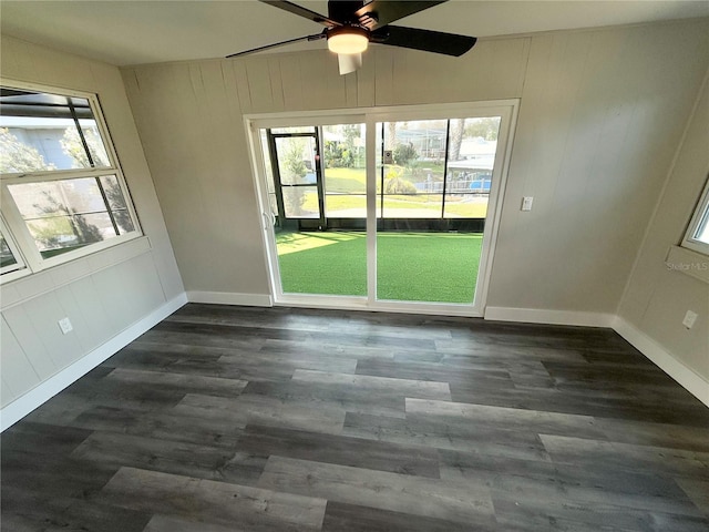 unfurnished room featuring ceiling fan, a healthy amount of sunlight, and dark hardwood / wood-style flooring