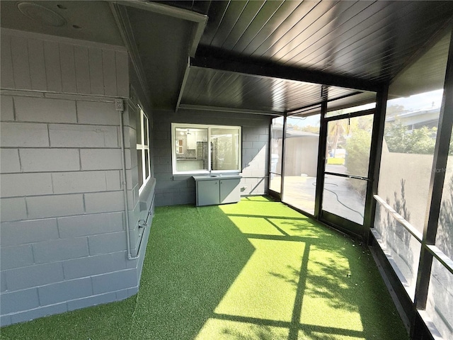 unfurnished sunroom featuring beam ceiling