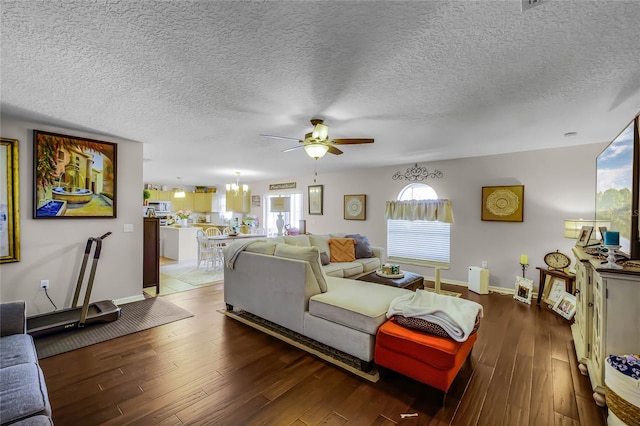 living area with dark wood-type flooring, a textured ceiling, and ceiling fan with notable chandelier