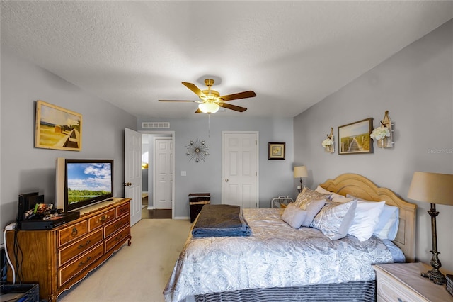 bedroom with ceiling fan, visible vents, a textured ceiling, and light colored carpet