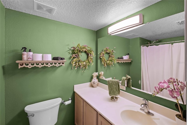 full bathroom featuring visible vents, vanity, toilet, and a textured ceiling