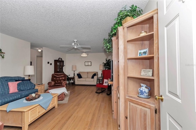 living room with ceiling fan, a textured ceiling, and light hardwood / wood-style flooring