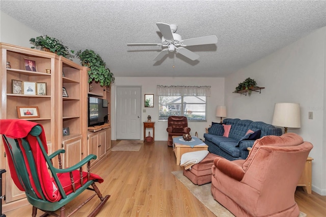 living room with ceiling fan, light hardwood / wood-style flooring, and a textured ceiling