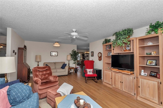 living room with ceiling fan, light hardwood / wood-style flooring, and a textured ceiling