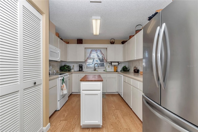 kitchen with sink, a kitchen island, white appliances, light hardwood / wood-style floors, and white cabinets