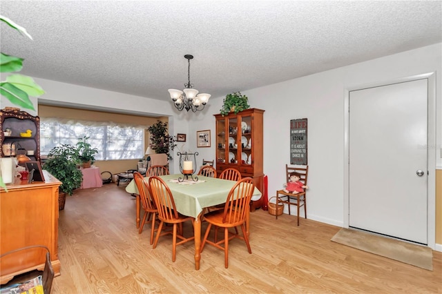 dining area featuring light hardwood / wood-style floors, a textured ceiling, and a notable chandelier