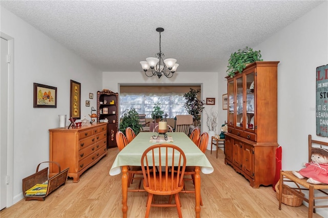 dining room with a notable chandelier, a textured ceiling, and light hardwood / wood-style flooring