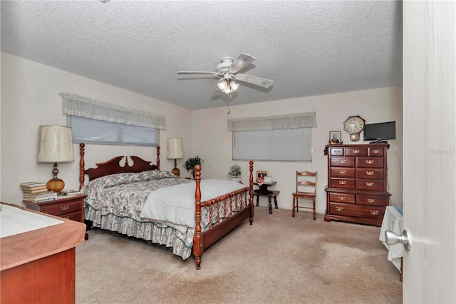 bedroom with ceiling fan, light colored carpet, and a textured ceiling