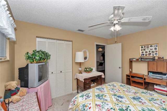 bedroom featuring ceiling fan, light colored carpet, a textured ceiling, and a closet