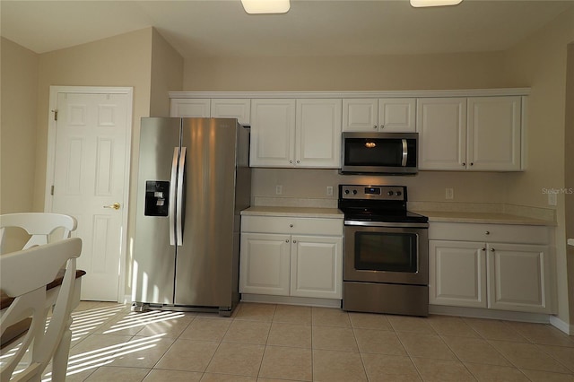 kitchen featuring stainless steel appliances, light tile patterned floors, and white cabinets