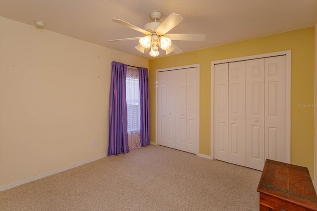 unfurnished bedroom featuring multiple closets, ceiling fan, and carpet floors