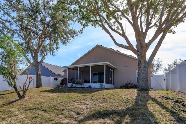 back of house with a sunroom and a lawn