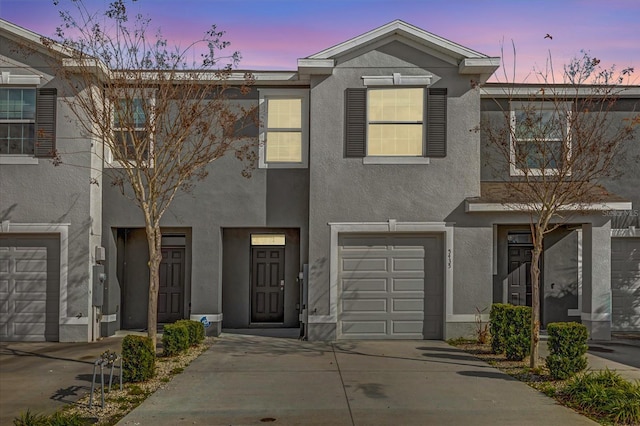 townhome / multi-family property with concrete driveway, an attached garage, and stucco siding