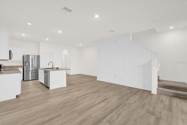 kitchen featuring sink, white cabinetry, appliances with stainless steel finishes, a kitchen island with sink, and light hardwood / wood-style floors