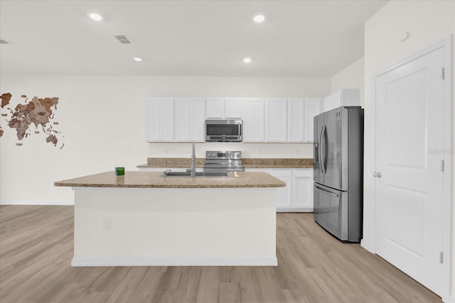 kitchen with appliances with stainless steel finishes, stone countertops, white cabinetry, and a center island with sink