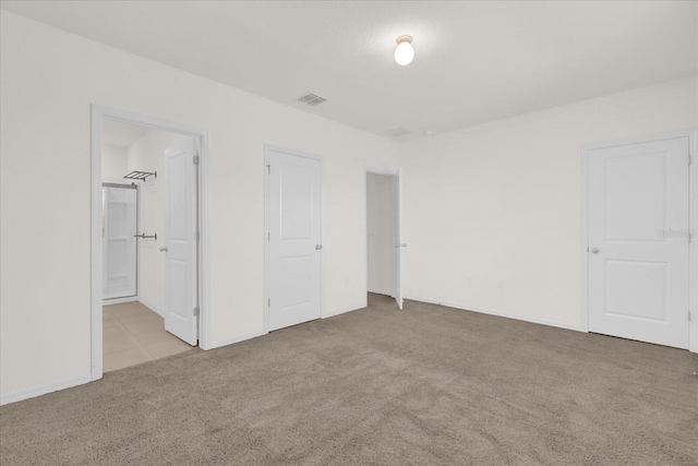 unfurnished bedroom featuring light carpet and ensuite bath