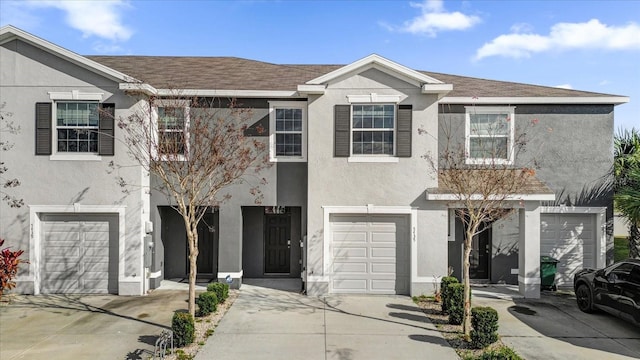 multi unit property with a shingled roof, driveway, an attached garage, and stucco siding