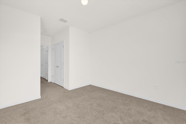 unfurnished room with light carpet, visible vents, and baseboards