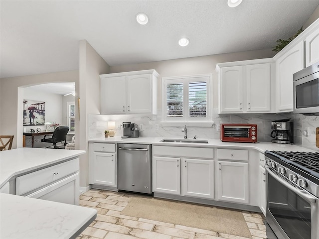 kitchen with stainless steel appliances, white cabinetry, sink, and decorative backsplash