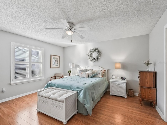 bedroom with ceiling fan, light hardwood / wood-style flooring, and a textured ceiling