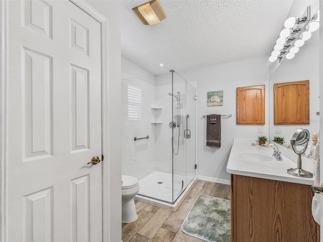 bathroom featuring toilet, a textured ceiling, vanity, a shower with door, and hardwood / wood-style floors